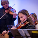 Ein elev som spelar fiolin i lag med læraren sin